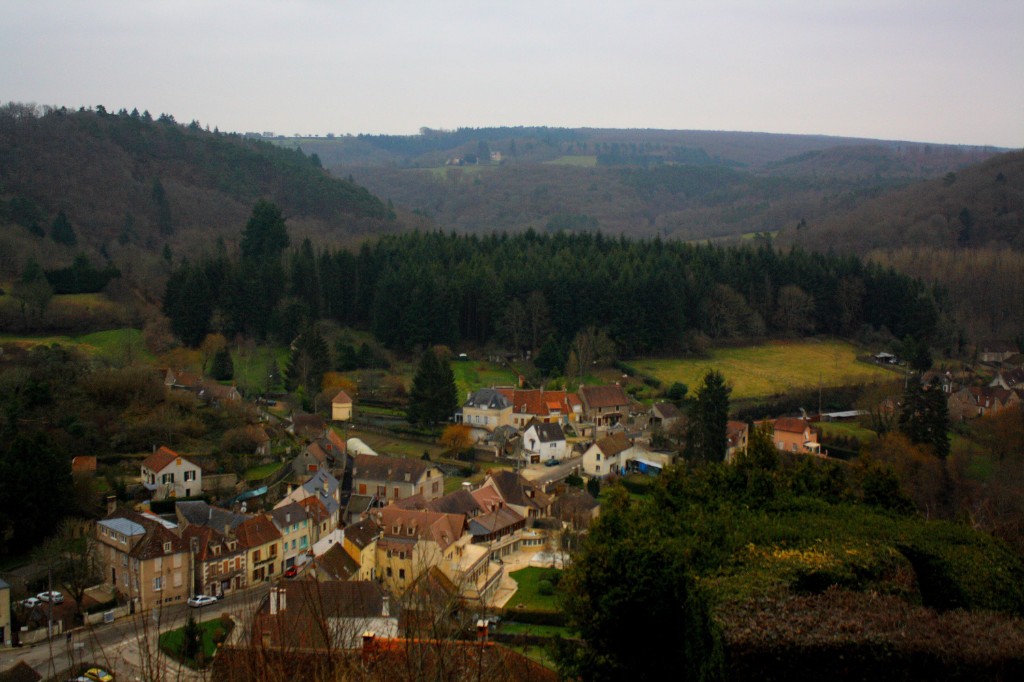 A French village with red-tiled roofs nestled in a green valley